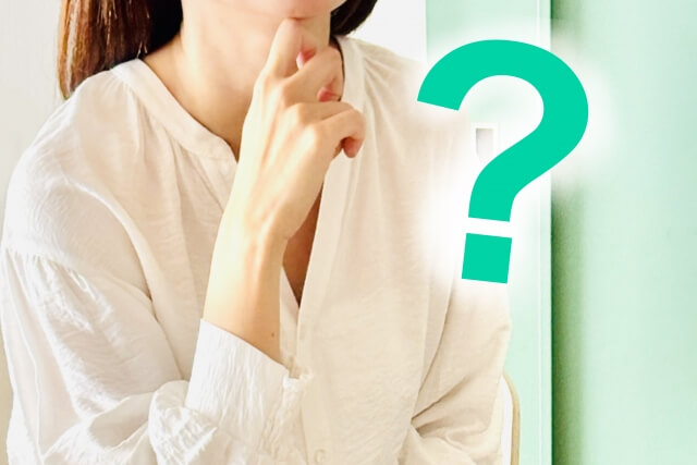 考え事をする白いシャツの女性